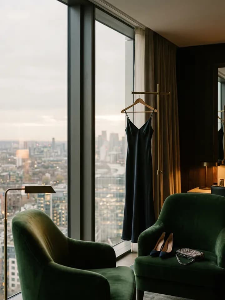 Vestido preto pendurado na janela de uma suíte de hotel ao anoitecer